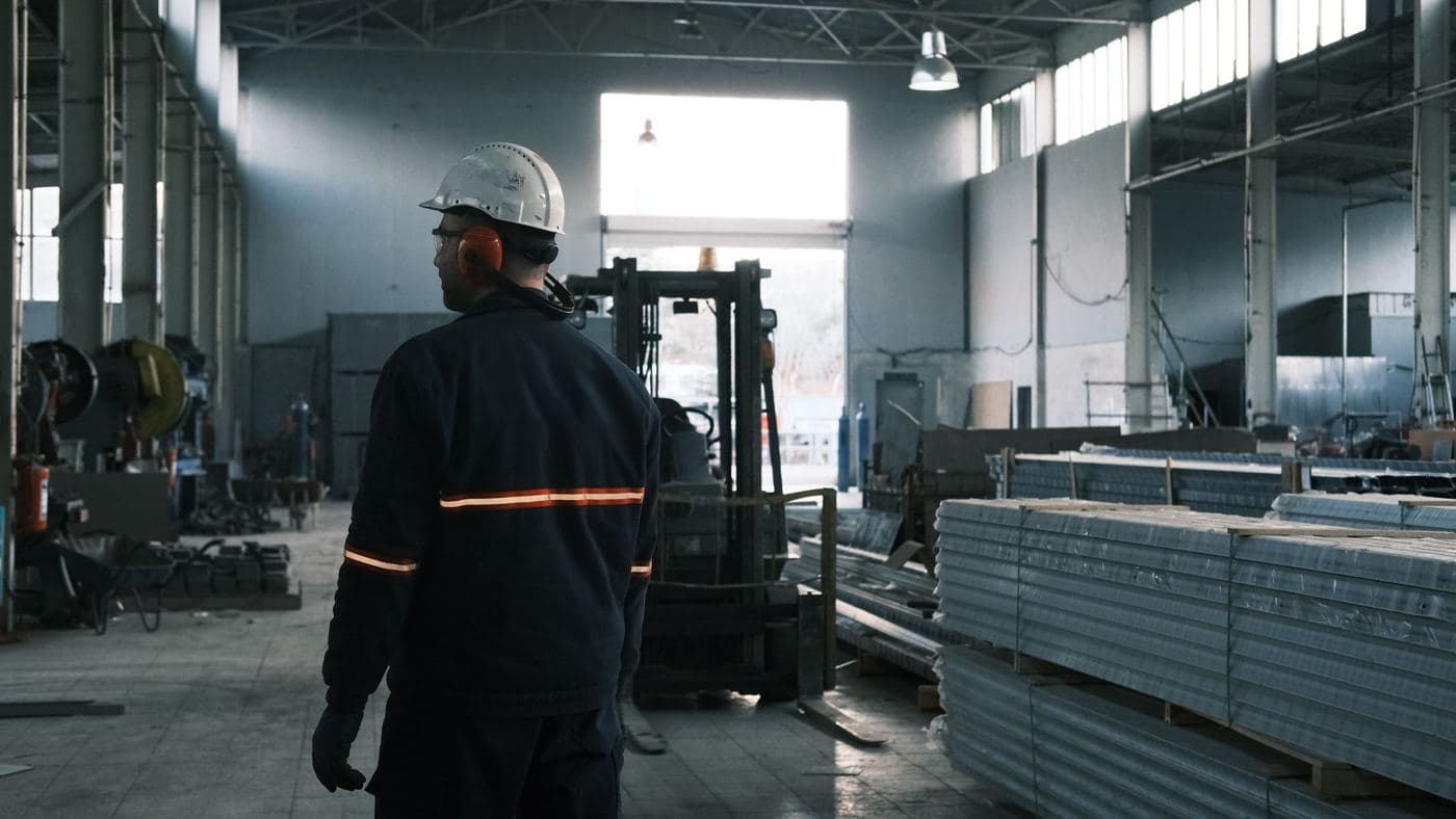 İstehsal sexində dəbilqəli işçi və forklift